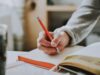 person-holding-orange-pen-1925536